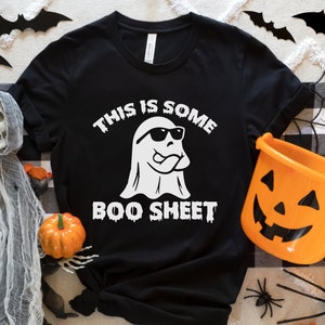 May include: Black t-shirt with a white ghost wearing sunglasses and the text "This is some boo sheet".