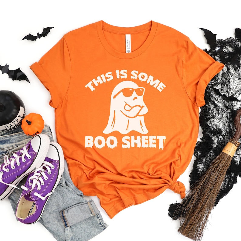 May include: Orange t-shirt with a white ghost wearing sunglasses and the text "This is some Boo Sheet".