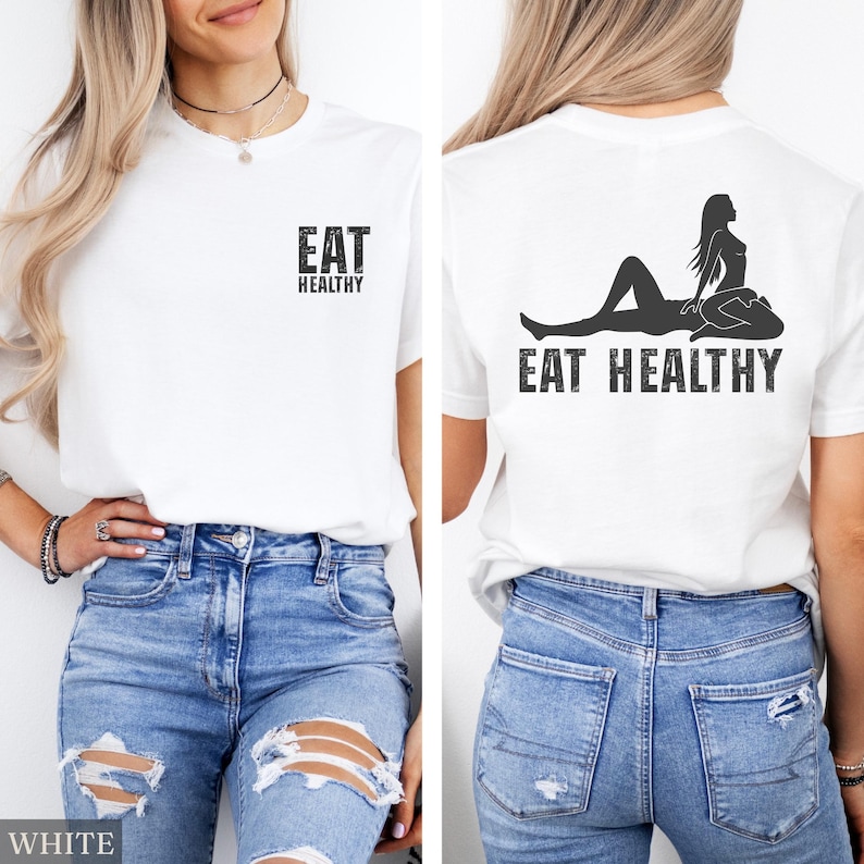 May include: White t-shirt with the text "EAT HEALTHY" on the front and back. The back of the shirt features a black graphic of a woman reclining. The front text is above the back text.