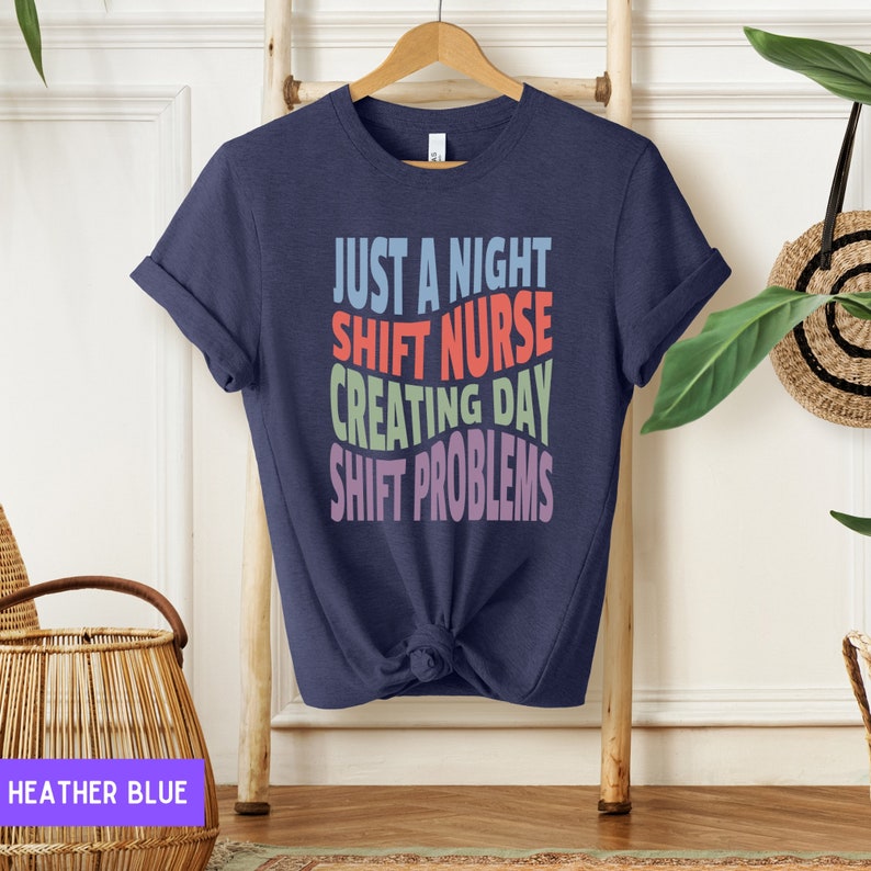 May include: A navy blue t-shirt with the text "Just a night shift nurse creating day shift problems" in colorful letters.