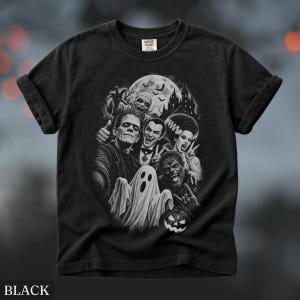 May include: A black short-sleeve t-shirt featuring a monochromatic graphic print of classic horror movie monsters including Frankenstein, Dracula, a mummy, a werewolf, and a ghost, set against a moonlit castle background with bats.