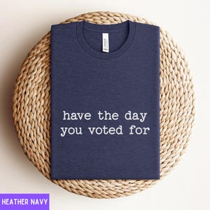 May include: A heather navy blue t-shirt with the text "have the day you voted for" printed in white.