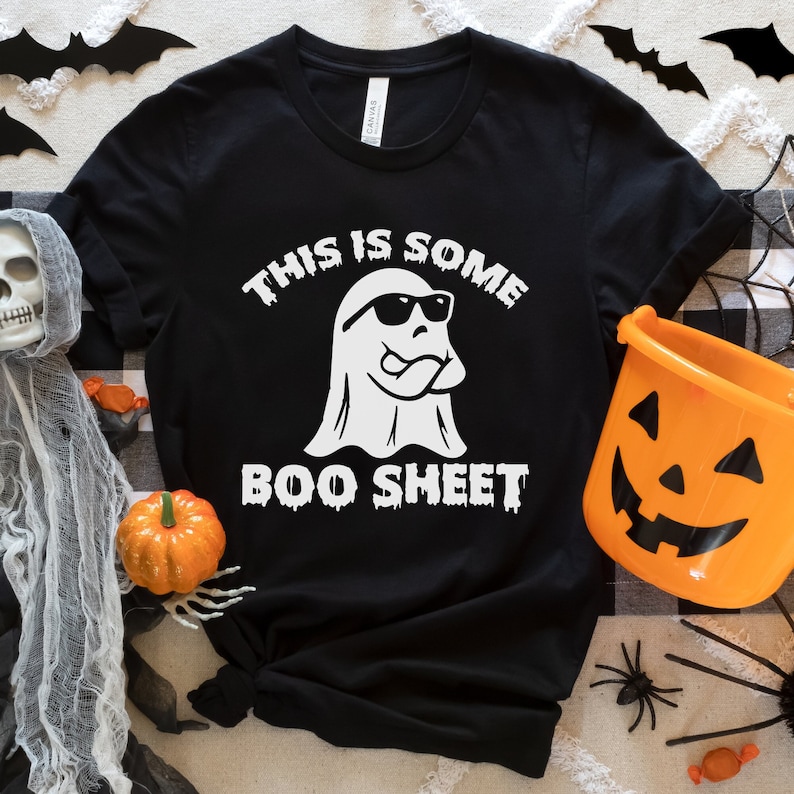May include: Black t-shirt with a white ghost wearing sunglasses and the text "This is some boo sheet".