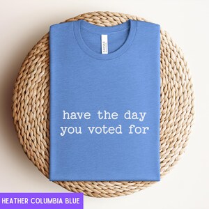 May include: A heather columbia blue t-shirt with the text "have the day you voted for" printed in white.