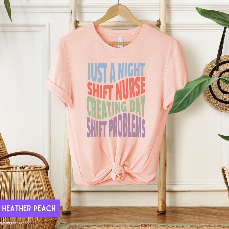 May include: A pink t-shirt with the text "Just a night shift nurse creating day shift problems" in rainbow colours.