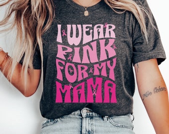 May include: A gray t-shirt with the text "I Wear Pink For My Mama" in pink and white lettering. The text is in a retro font style and includes pink ribbon symbols.