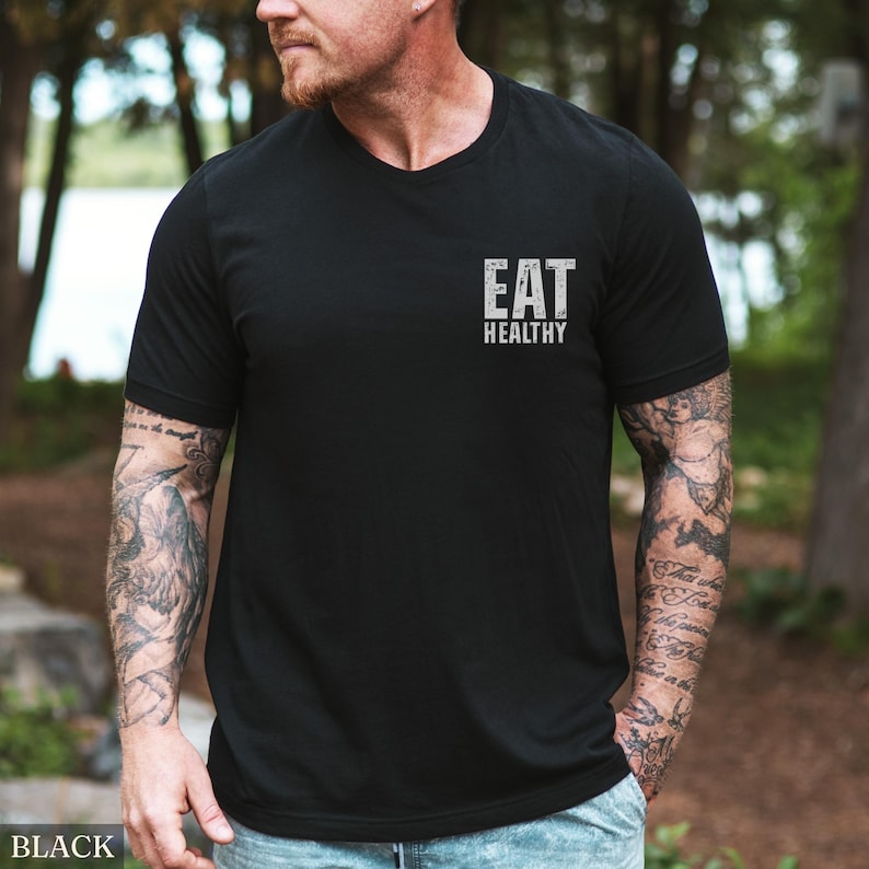 May include: Black crew neck t-shirt with the text "EAT HEALTHY" printed in white. The shirt is made of a soft material and is suitable for casual wear. The shirt is a versatile piece for everyday outfits.