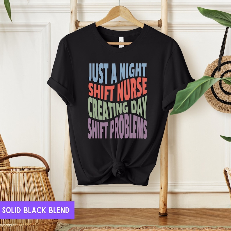 May include: Black t-shirt with the text "Just a night shift nurse creating day shift problems" in rainbow colours.