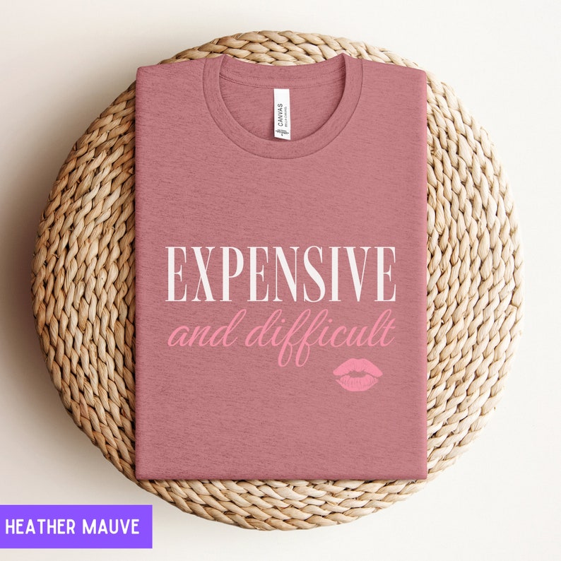 May include: Heather mauve t-shirt with the text "EXPENSIVE and difficult" in white and a pink lip print.