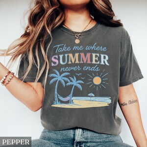 May include: A gray t-shirt with the text "Take me where SUMMER never ends" in a colorful font. The graphic includes palm trees, a hammock, a sun, and the ocean. The shirt is a relaxed fit.