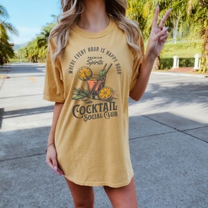 May include: A yellow t-shirt with a graphic of a cocktail glass with a lemon wedge and the text "Where every hour is happy hour, Premium Spirits, Cocktail Social Club".