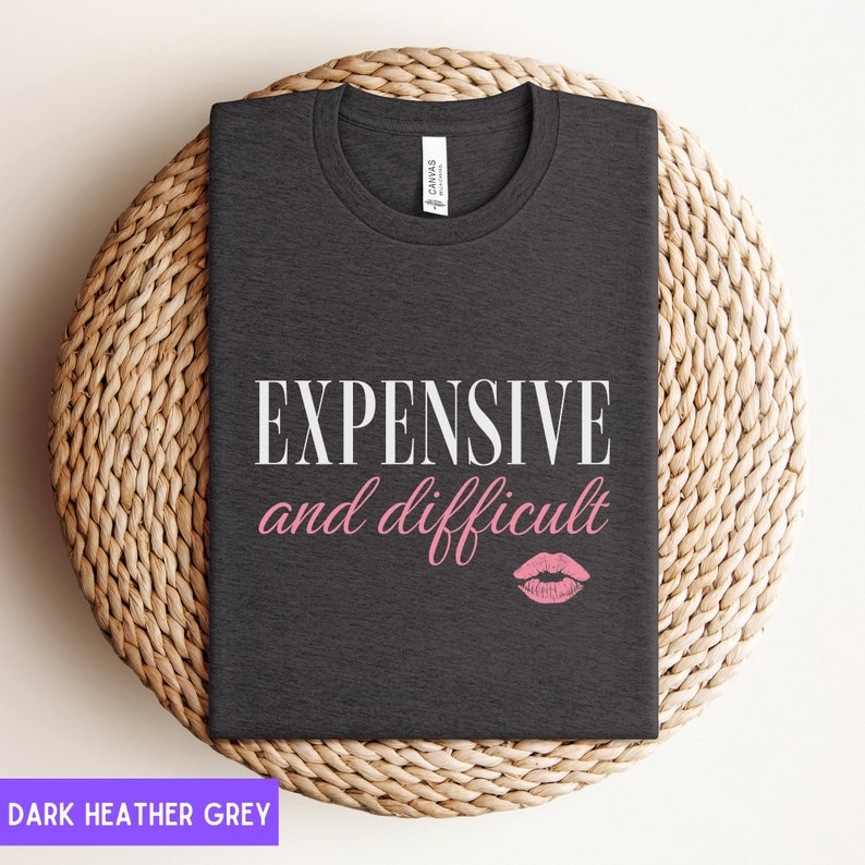 May include: Dark heather grey t-shirt with the text "EXPENSIVE and difficult" in white and a pink lipstick print.