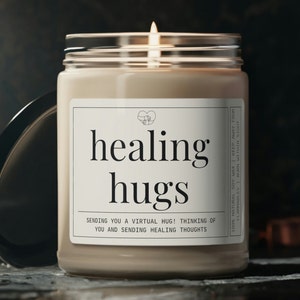 May include: A beige candle in a glass jar with a white label that reads "healing hugs" and "Sending you a virtual hug! Thinking of you and sending healing thoughts".