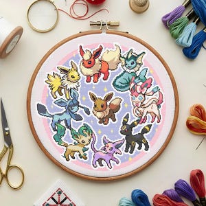 Puede incluir: Un bastidor de bordado circular de madera que contiene un patrón de punto de cruz de nueve coloridas criaturas de evolución de Eevee dispuestas en círculo alrededor de un Eevee marrón central sobre un fondo morado claro con estrellas amarillas.