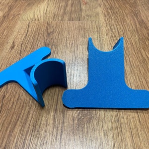 May include: Two blue plastic pieces that can be assembled to create a stand for a phone or tablet.