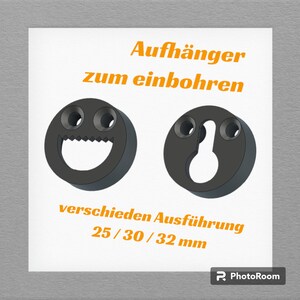 Op de afbeelding: Twee zwarte plastic wandhaken om spullen aan op te hangen. De haken zijn ontworpen om in een muur te worden geschroefd. De tekst op de afbeelding luidt "Aufhänger zum einbohren" en "verschieden Ausführung 25/30/32 mm".