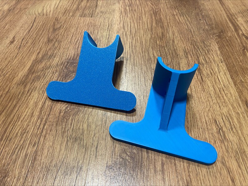 May include: Two blue plastic stands for holding items, such as a phone or tablet, on a wooden surface.