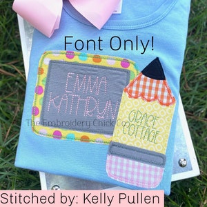 Puede incluir: Una camiseta azul claro con un diseño bordado en amarillo, gris y rosa de una pizarra con el texto "Emma Kathryn" y un lápiz con el texto "Grade Cottage". El texto "Font Only!" está por encima del diseño. El texto "The Embroidery Chick Co." está debajo del diseño. El texto "Stitched by: Kelly Pullen" está debajo de la camiseta.