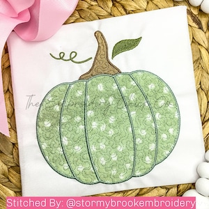 Puede incluir: Calabaza verde con lunares blancos y un tallo marrón. La calabaza está bordada en una tela blanca con la palabra "ee" encima. El texto "Stitched By: @stormybrookeembroidery" está en la parte inferior de la imagen.
