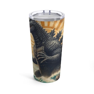 May include: A stainless steel tumbler with a black and white illustration of Godzilla emerging from the ocean waves. The background is a vintage-style sunrise with a red and yellow color scheme.
