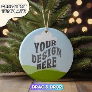 May include: A white ceramic Christmas ornament with a blue sky, green grass, and white cloud design. The text "YOUR DESIGN HERE" is printed in black on the ornament.