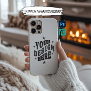 Puede incluir: Maqueta de funda de teléfono blanca con un diseño negro que dice "YOUR DESIGN HERE" con estrellas alrededor del texto. La funda está siendo sostenida por una mano en un suéter blanco.