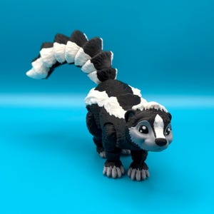 May include: A black and white skunk figurine with a long, bushy tail. The figurine has a cute, cartoonish face with large eyes and a small nose.