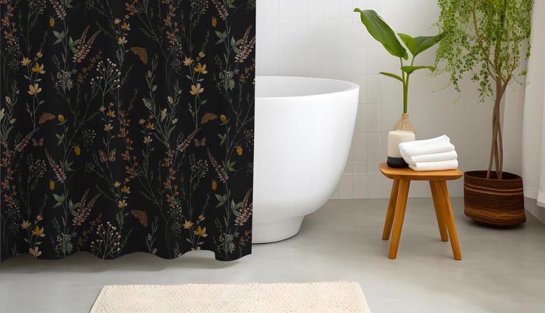 May include: A black shower curtain with a floral pattern featuring yellow, brown, and green flowers and butterflies. The bathroom includes a white bathtub, a wooden stool with white towels, and potted plants, creating a serene, nature-inspired aesthetic.