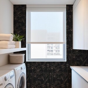 Puede incluir: Un papel tapiz floral blanco y negro con un delicado dise&ntilde;o de l&iacute;neas. El papel tapiz presenta un patr&oacute;n repetitivo de flores y hojas en un estilo minimalista. El papel tapiz se muestra en un ba&ntilde;o con una lavadora blanca y una ventana con vista a una ciudad.