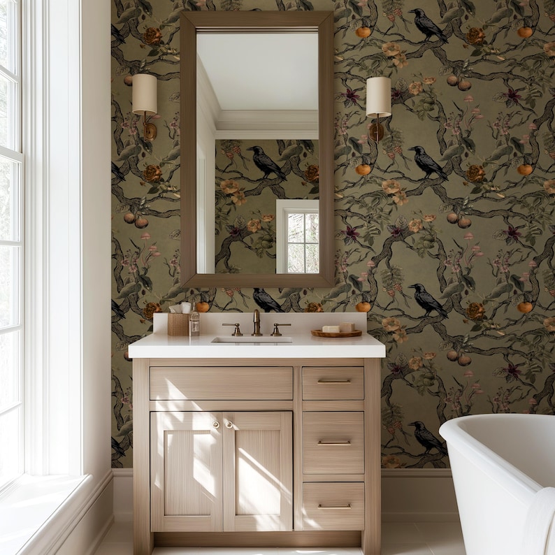 May include: A bathroom vanity with a light wood finish, a white countertop, and a large mirror. The wallpaper features a pattern of black birds, flowers, and fruit on a green background. Two sconces flank the mirror.