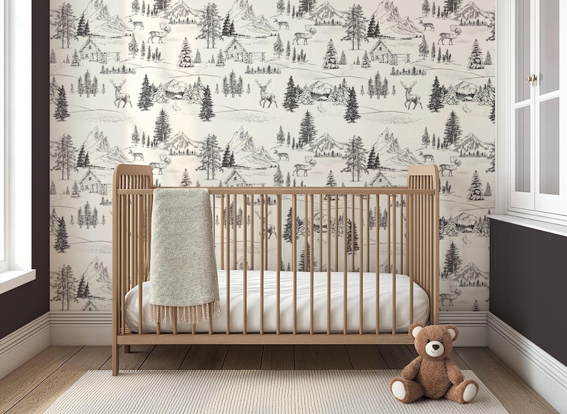 Puede incluir: Una cuna de madera clara con un colch&oacute;n blanco y una manta gris. La cuna est&aacute; frente a una pared con un papel pintado con un paisaje de monta&ntilde;a y bosque en blanco y negro. Un oso de peluche marr&oacute;n est&aacute; en el suelo.