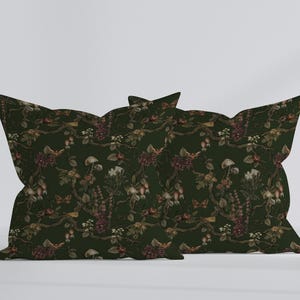 May include: Two decorative pillows with a dark green floral pattern. The pattern includes flowers, mushrooms, and butterflies in shades of brown, red, and white. The pillows are rectangular with a unique, scalloped edge.