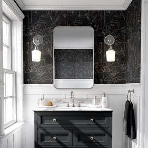 Puede incluir: Un papel tapiz floral blanco y negro con un contorno dorado. El papel tapiz est&aacute; en un ba&ntilde;o con un tocador negro y un espejo sobre el lavabo.