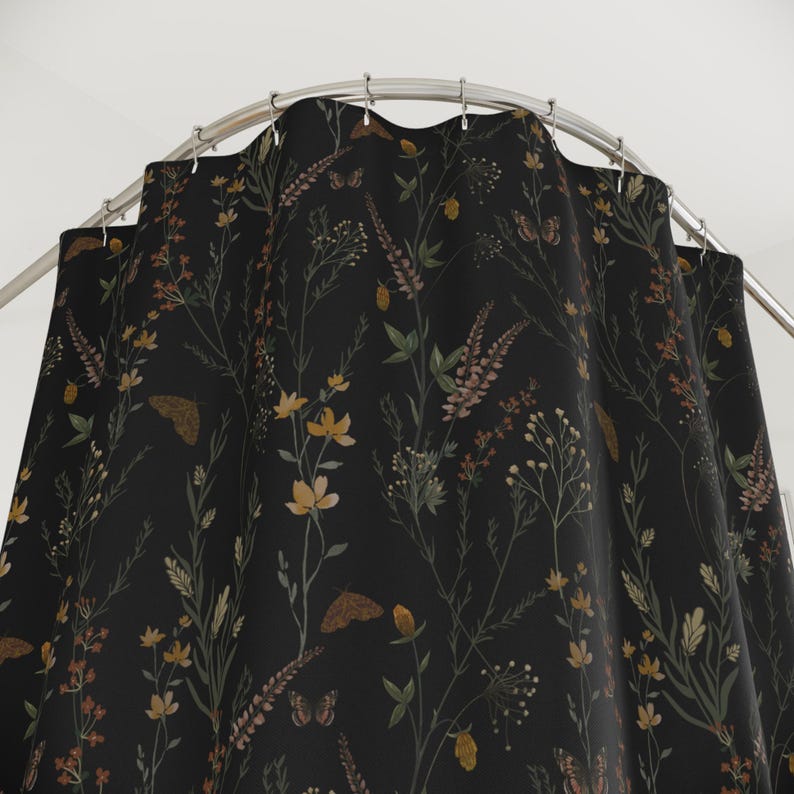 May include: A black shower curtain with a botanical design. The pattern features various wildflowers, butterflies, and foliage in shades of yellow, brown, and green. The curtain hangs from a curved, silver-colored shower rod.