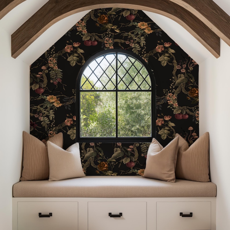 May include: A cozy window seat with a black floral wallpaper backdrop. The window has a black grid pattern. Beige pillows and a bench cushion sit atop white storage drawers. Wooden beams frame the window.