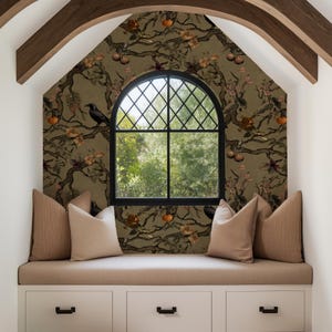 May include: A cozy window seat with a patterned wallpaper featuring branches, flowers, and fruit. A black arched window with a diamond grid is centered. Beige cushions and pillows sit atop a white storage unit with black handles.