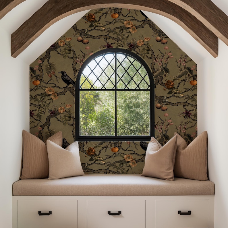 May include: A cozy window seat with a patterned wallpaper featuring branches, flowers, and fruit. A black arched window with a diamond grid is centered. Beige cushions and pillows sit atop a white storage unit with black handles.