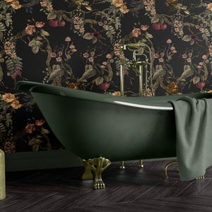 May include: An olive green clawfoot bathtub with gold fixtures and a gray towel. The bathroom features a dark floral wallpaper and two olive green decorative bottles. The floor is dark wood.