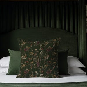 May include: A bed with a dark green headboard and matching bedding. Decorative pillows with floral patterns in shades of green, brown, and burgundy are arranged on the bed. The room has a luxurious, vintage aesthetic.