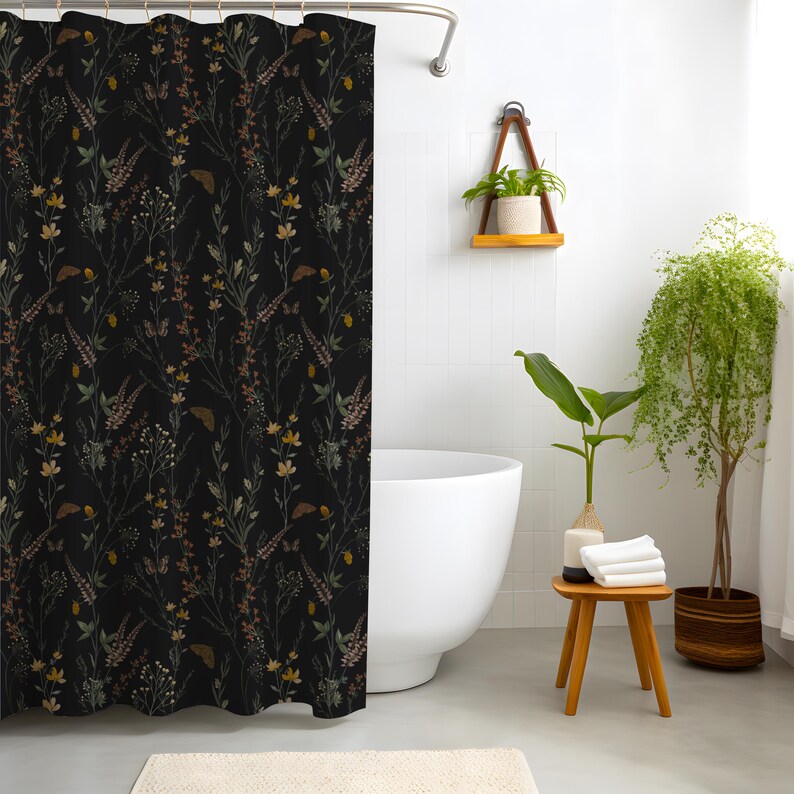 May include: A black shower curtain with a botanical pattern featuring wildflowers in shades of yellow, brown, and green. The curtain is hanging in a bathroom with a white tub and a small wooden stool.
