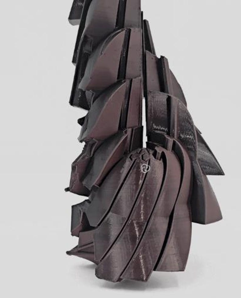 Pode incluir: Uma escultura abstrata marrom escuro com um design geom&eacute;trico em camadas. A obra de arte apresenta m&uacute;ltiplas formas curvas e angulares, criando uma apar&ecirc;ncia din&acirc;mica e texturizada. A pe&ccedil;a est&aacute; sobre um fundo branco liso.