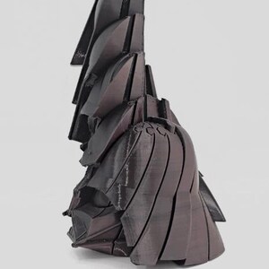 Pode incluir: Uma escultura abstrata marrom escuro com um design geom&eacute;trico em camadas. A obra de arte apresenta uma s&eacute;rie de formas angulares sobrepostas que criam uma sensa&ccedil;&atilde;o de profundidade e textura. A forma da escultura lembra papel ou tecido dobrado.