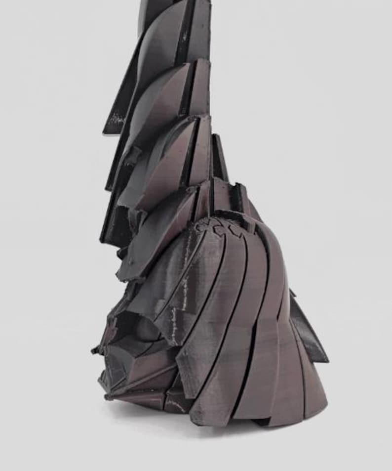 Pode incluir: Uma escultura abstrata marrom escuro com um design geom&eacute;trico em camadas. A obra de arte apresenta uma s&eacute;rie de formas angulares sobrepostas que criam uma sensa&ccedil;&atilde;o de profundidade e textura. A forma da escultura lembra papel ou tecido dobrado.