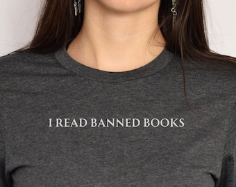 May include: Dark gray t-shirt with the text "I READ BANNED BOOKS" in white. The shirt has a crew neck and short sleeves. The text is centered on the chest.