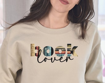 May include: A beige sweatshirt with the text "book lover" printed on the front. The text is made up of images of book spines.