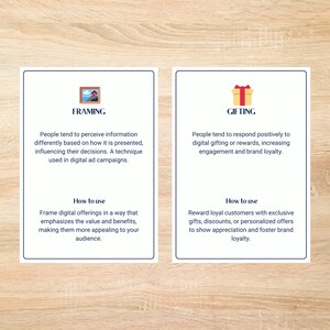 May include: Two blue cards with white text and illustrations. The card on the left has a picture of a house and the text "Framing". The card on the right has a picture of a gift box and the text "Gifting". Both cards have text explaining the concepts of framing and gifting in marketing.