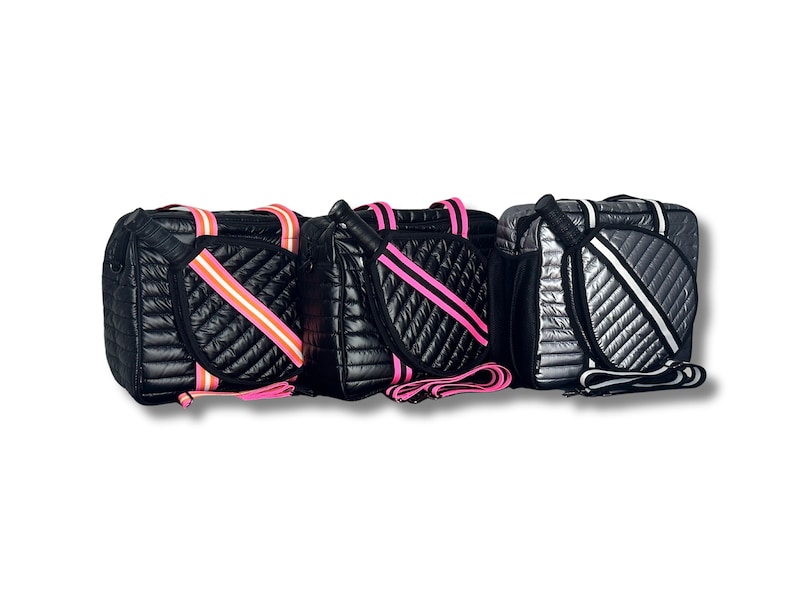 Puede incluir: Tres bolsas de p&aacute;del acolchadas de color negro y plateado con correas rosas y blancas. Las bolsas tienen un bolsillo acolchado en el lateral para una pala.