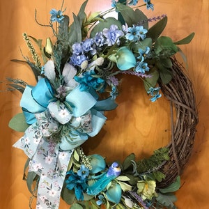Grapevine Wreath using Teal florals and Ribbon bow to match. Moss, greenery and a feathered bird complete this beautiful wreath