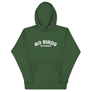 Könnte beinhalten: Ein waldgrüner Kapuzenpullover mit einer Kängurutasche auf der Vorderseite und langen Ärmeln. Auf der Brust befindet sich der Text GO BIRDS in einer weißen, gebogenen Schrift mit grauem Umriss und dem Wort DICKHEAD in kleineren weißen Buchstaben.