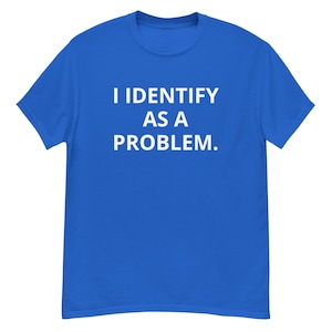Puede incluir: Camiseta azul real con el texto blanco "I IDENTIFY AS A PROBLEM." La camiseta tiene mangas cortas y cuello redondo. El texto está centrado en la parte delantera de la camiseta.